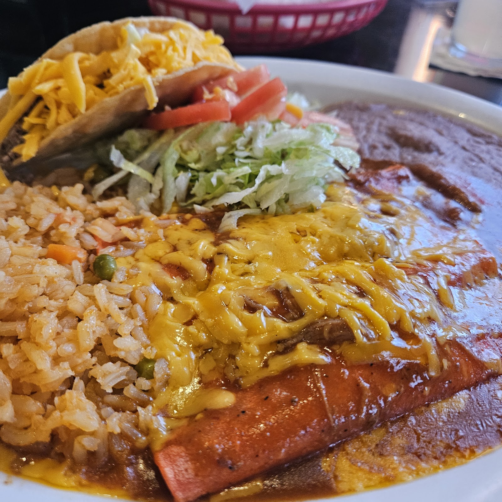 Enchilada plate with rice, beans and a crispy taco